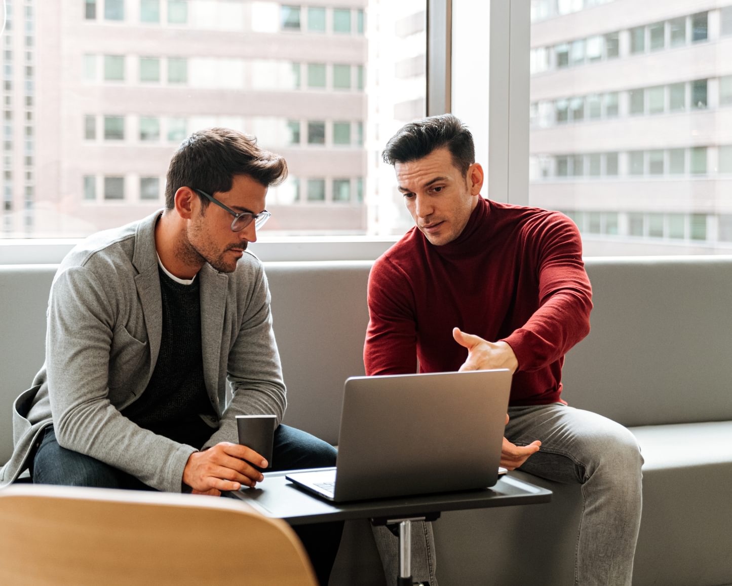 Two salespeople looking at a laptop, while the screen shows them moving a contact from the Interested column to the Engaged column in the ActiveCampaign CRM.