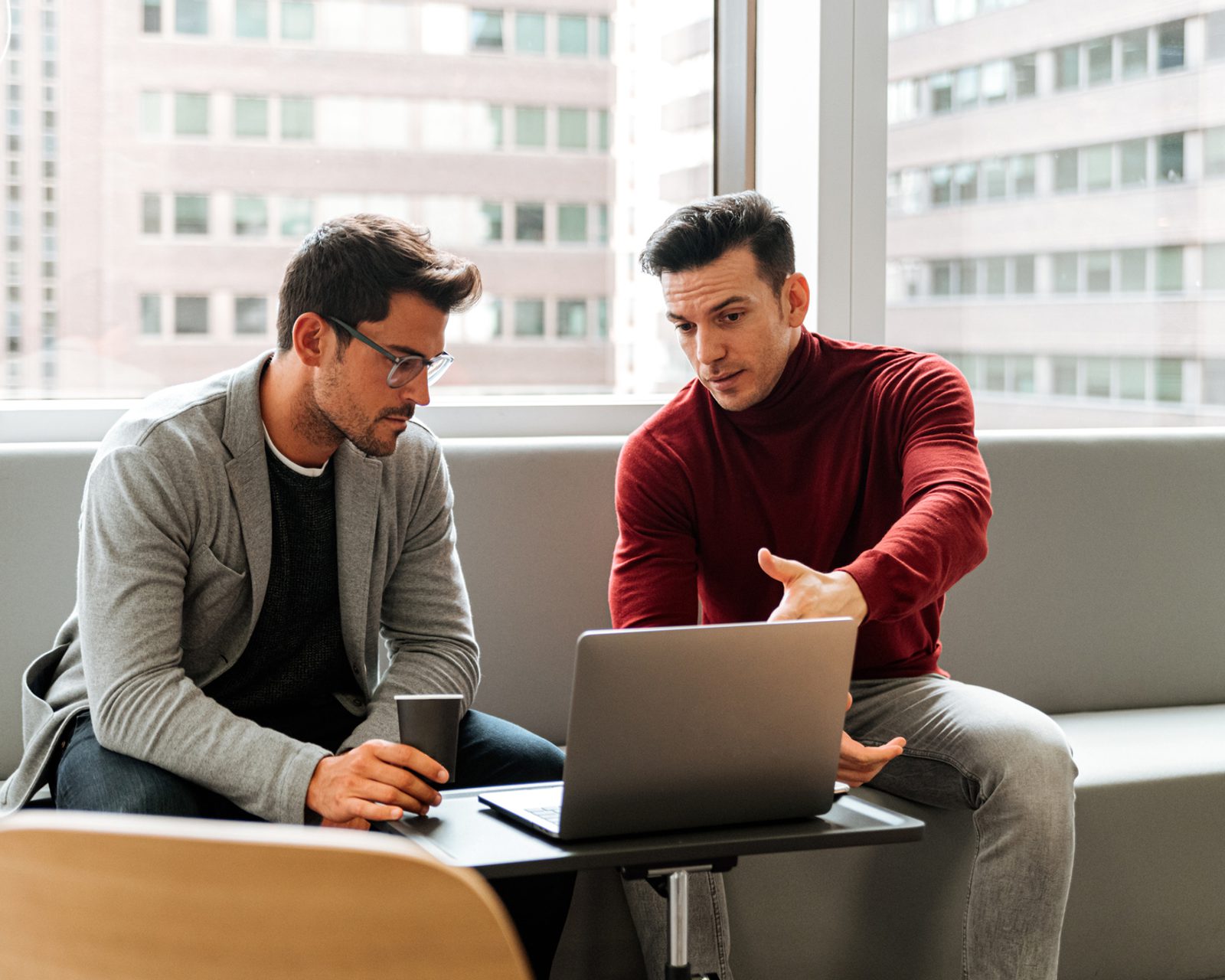Two salespeople looking at a laptop, while the screen shows them moving a contact from the Interested column to the Engaged column in the ActiveCampaign CRM.