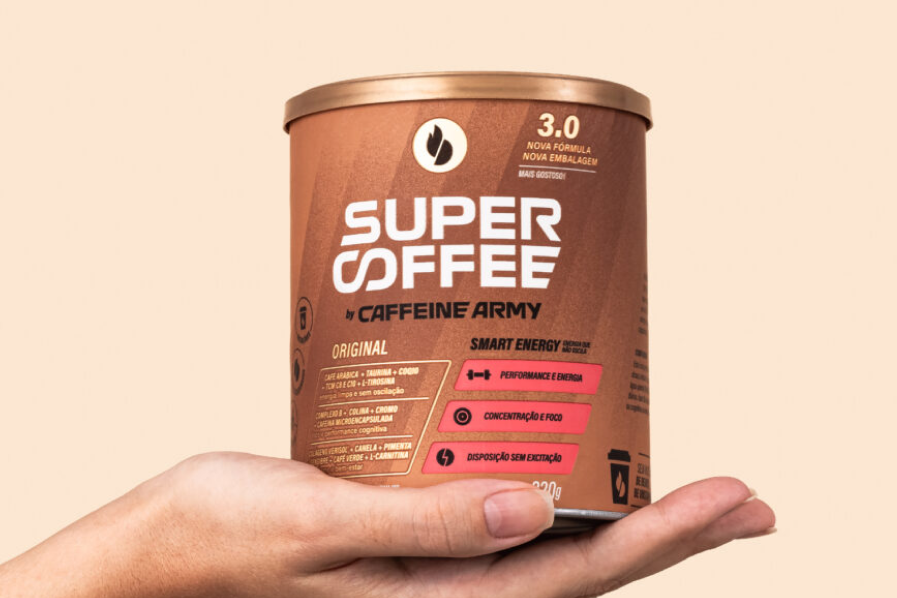 A hand holding a tub of Caffeine Army Super Coffee grounds.