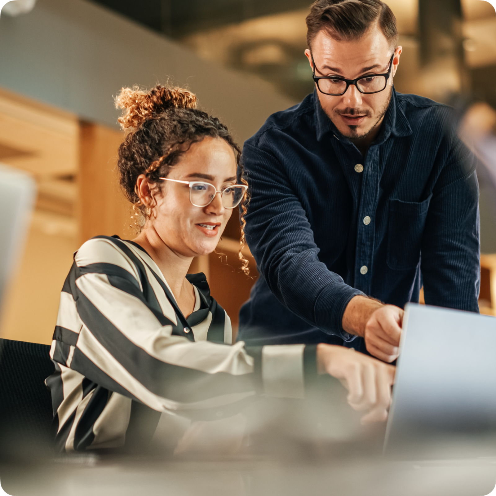 Two professionals pointing to a laptop screen discussing important business matters.